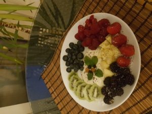 Superfruit light dinner that makes you sleep better: Kiwi, blueberries, raspberries, strawberries with grated coconut, pineapple with chocolate pepper, vanilla soy yogurt with vanilla grinder on top, almonds and mint