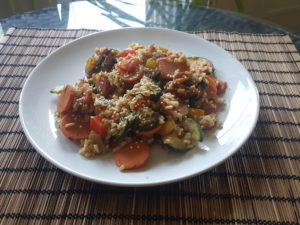 Wok of brown rice, yellow and red bell pepper, carrot, zucchini, ginger, cloves, cardamom, pepper