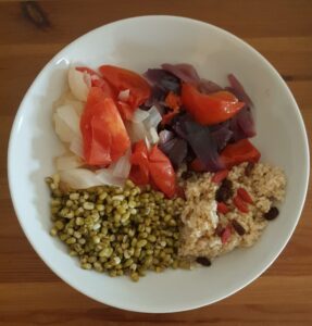 Proteins, carbohydrates, vegetables vegetarian dish. Red and sweet white onions, Spanish and Italian bio tomatoes, bulgur with raisins and gogi berries, mung beans, 5 peppers (grey, pink, black, red, white) 